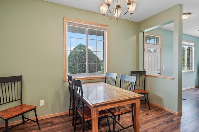 dining space featuring baseboards, a notable chandelier, and wood finished floors