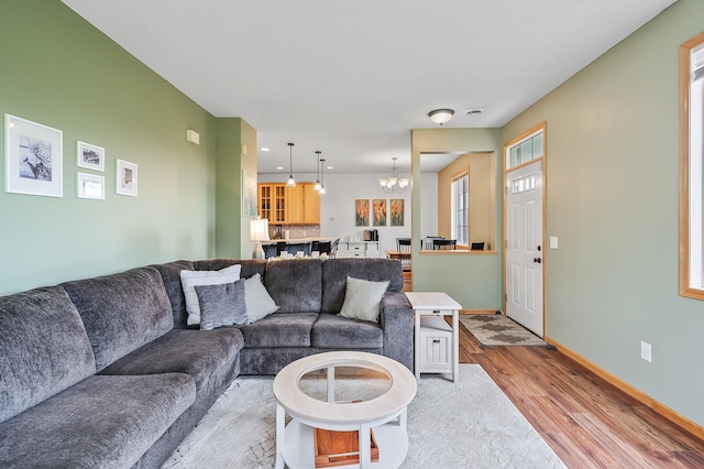 living room with recessed lighting, a notable chandelier, light wood-style flooring, and baseboards