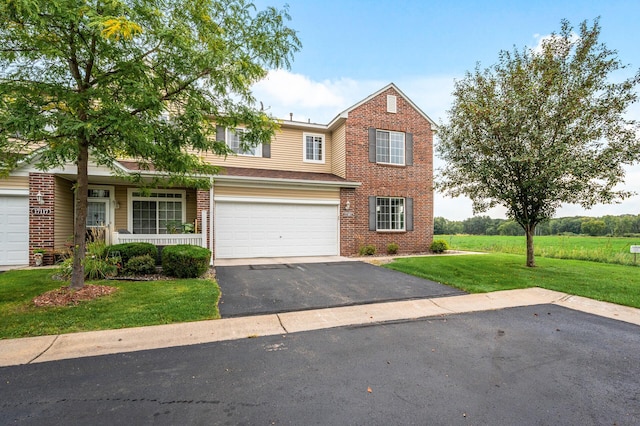 traditional-style home featuring brick siding, a garage, driveway, and a front yard