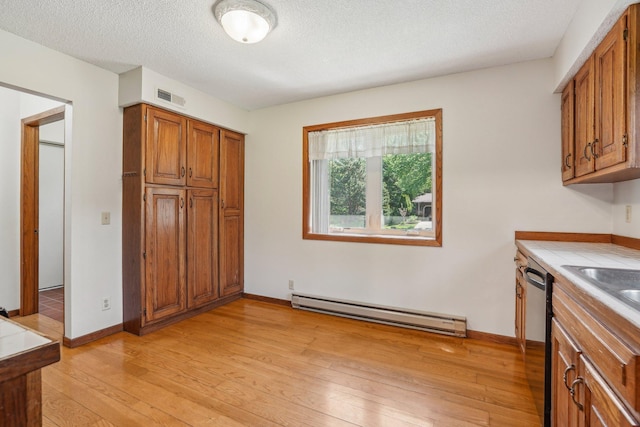 2605 Forest St, Maplewood, MN 55109 - kitchen featuring baseboard heating, brown cabinets, dishwasher, light wood-style flooring, and light countertops