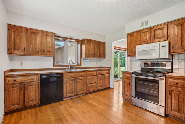 2605 Forest St, Maplewood, MN 55109 - kitchen with white microwave, black dishwasher, electric stove, a sink, and brown cabinetry