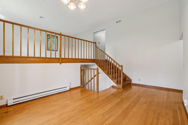 2605 Forest St, Maplewood, MN 55109 - unfurnished living room with a baseboard heating unit, hardwood / wood-style flooring, a chandelier, stairway, and baseboards