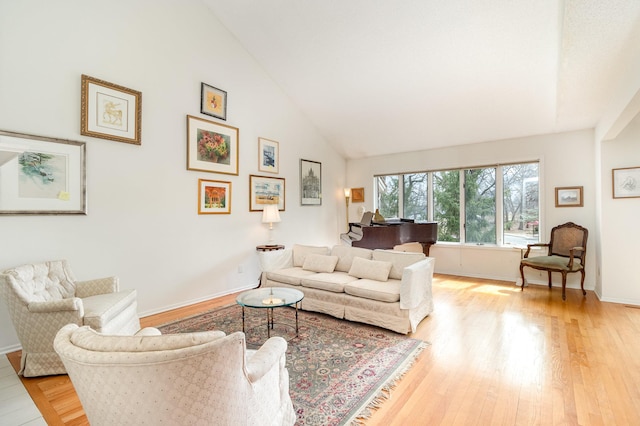 living room featuring baseboards, high vaulted ceiling, and light wood-style floors