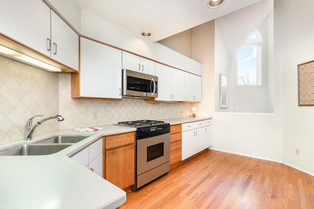kitchen with light countertops, appliances with stainless steel finishes, a sink, and white cabinetry
