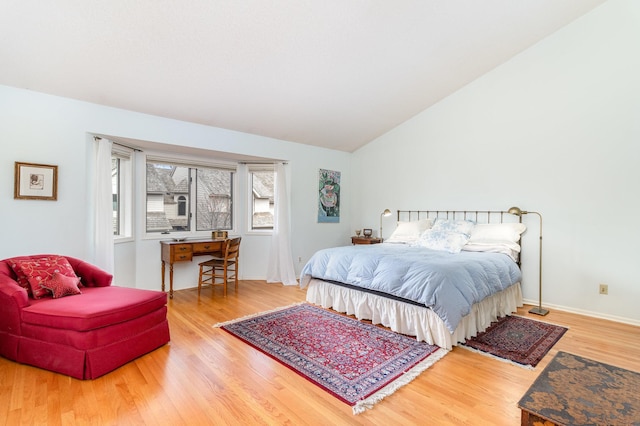 bedroom featuring baseboards, wood finished floors, and lofted ceiling