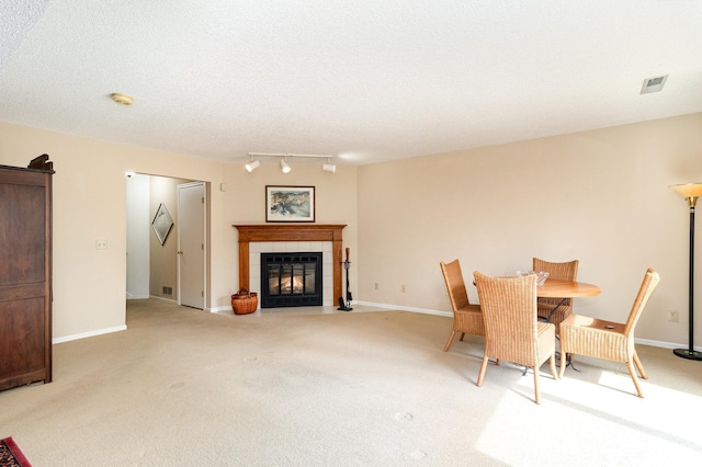 dining area with a tile fireplace, visible vents, light colored carpet, and track lighting
