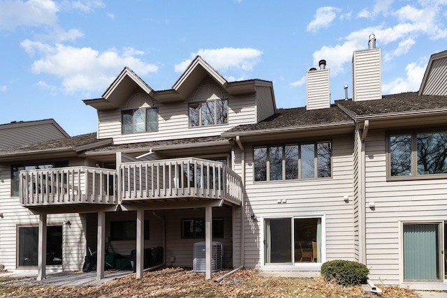back of house featuring a chimney, a deck, and central AC