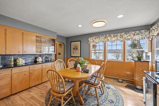 W3527 2nd St, Maiden Rock, WI 54750 - dining room with a textured ceiling, a wainscoted wall, light wood-style floors, beverage cooler, and arched walkways