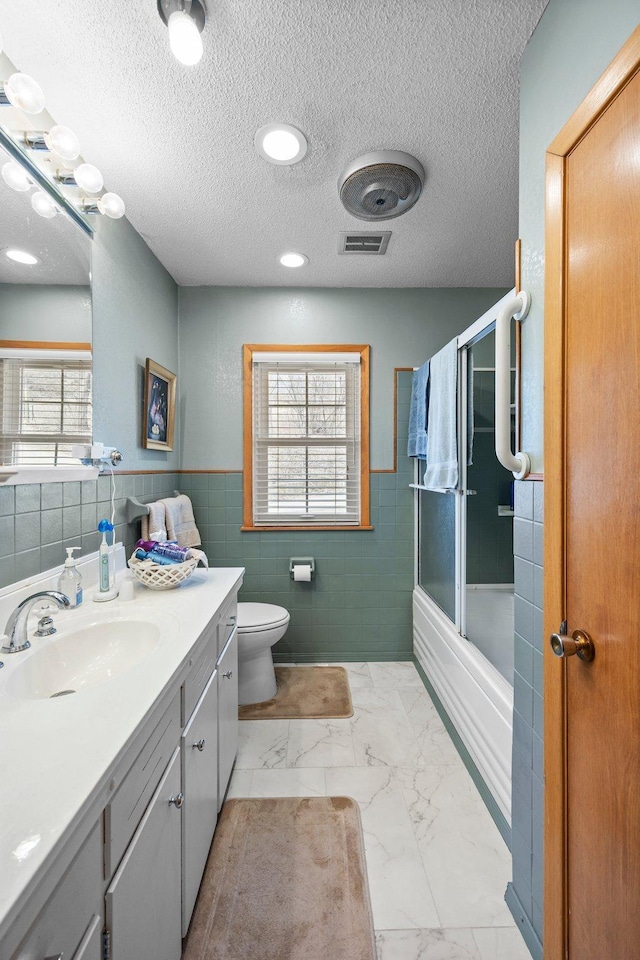 W3527 2nd St, Maiden Rock, WI 54750 - bathroom with tile walls, vanity, plenty of natural light, shower / bath combination with glass door, and toilet