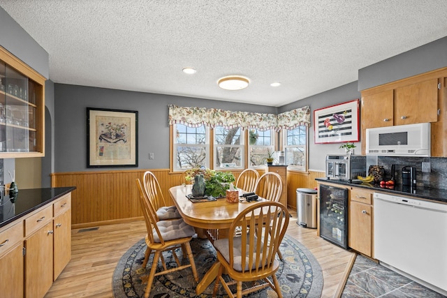 W3527 2nd St, Maiden Rock, WI 54750 - dining room with beverage cooler, wainscoting, a textured ceiling, wood walls, and light wood-type flooring