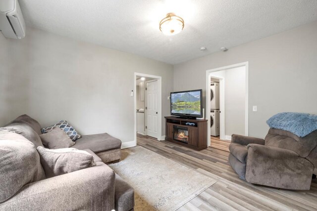 588 Van Buren Ave, Saint Paul, MN 55103 - living room featuring stacked washer / drying machine, an AC wall unit, light wood-style flooring, and baseboards