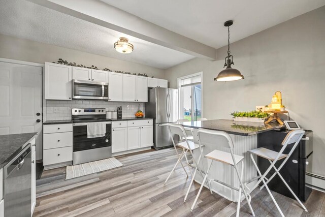 588 Van Buren Ave, Saint Paul, MN 55103 - kitchen featuring stainless steel appliances, tasteful backsplash, light wood-type flooring, white cabinets, and pendant lighting