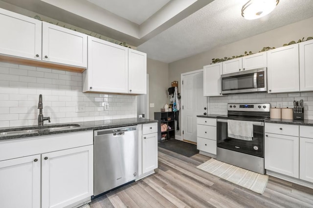 588 Van Buren Ave, Saint Paul, MN 55103 - kitchen featuring stainless steel appliances, a sink, white cabinets, light wood-type flooring, and a textured ceiling