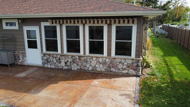 18063 Bernard Trl, Brainerd, MN 56401 - view of side of home featuring stone siding, a patio area, and roof with shingles