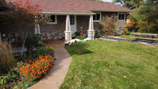 18063 Bernard Trl, Brainerd, MN 56401 - view of front facade featuring stone siding, a front lawn, covered porch, and a shingled roof