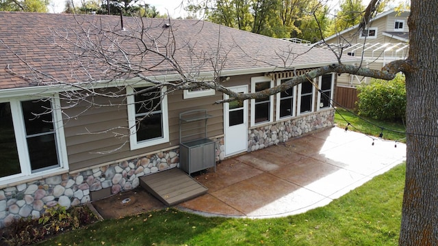 18063 Bernard Trl, Brainerd, MN 56401 - rear view of house with stone siding, roof with shingles, and a patio