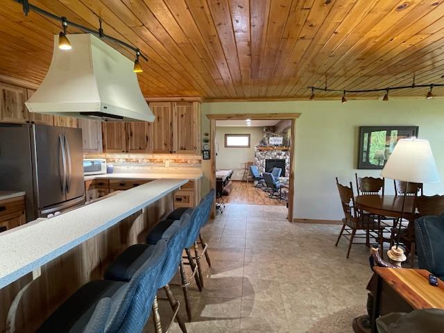 18063 Bernard Trl, Brainerd, MN 56401 - kitchen featuring freestanding refrigerator, custom exhaust hood, track lighting, light countertops, and wood ceiling