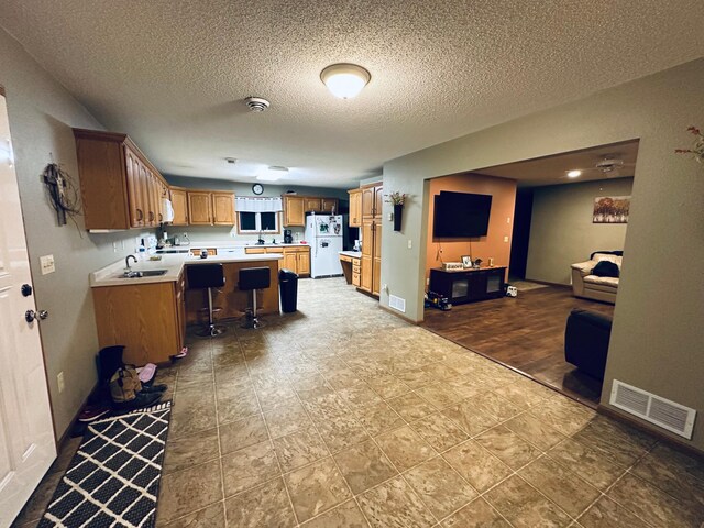 kitchen featuring open floor plan, visible vents, light countertops, and freestanding refrigerator