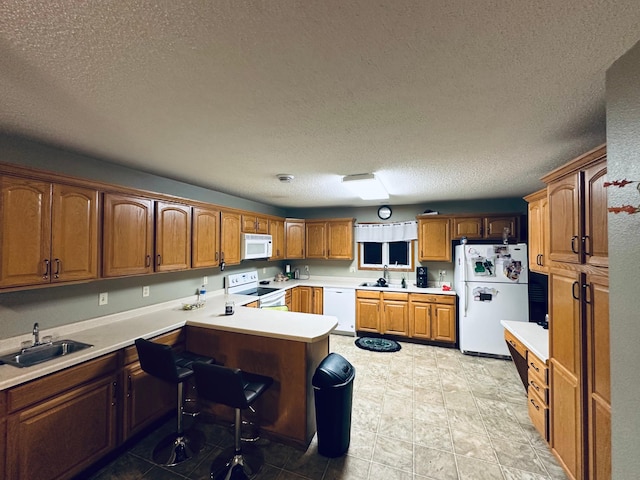 kitchen with white appliances, light countertops, a sink, and a peninsula
