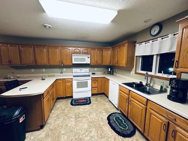 kitchen featuring a textured ceiling, light countertops, a sink, and white appliances