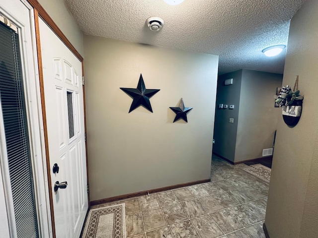 corridor featuring baseboards and a textured ceiling