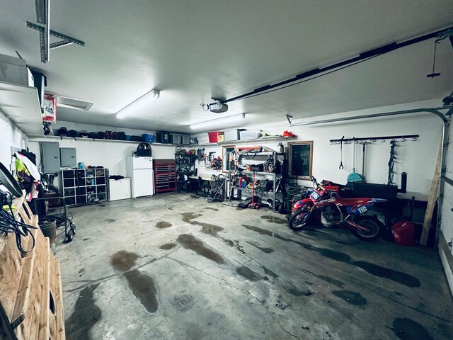 garage with electric panel, a garage door opener, and freestanding refrigerator