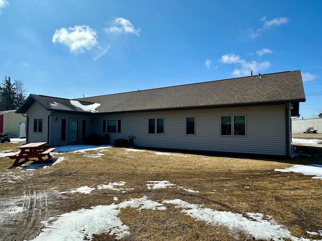 snow covered property with a shingled roof and a patio
