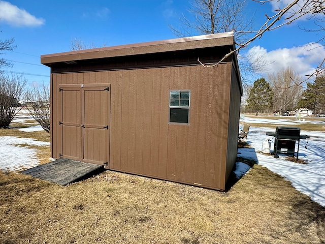 snow covered structure with a shed and an outdoor structure