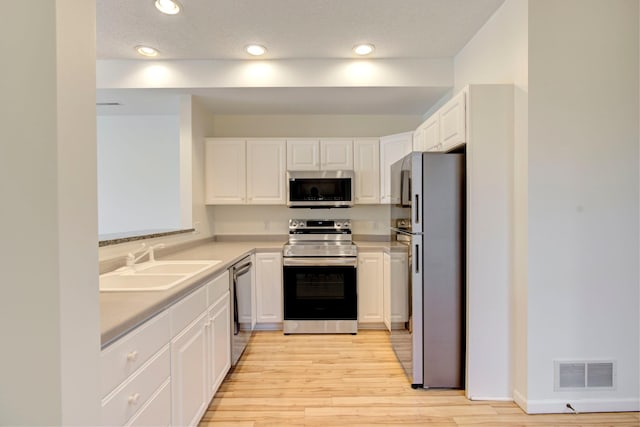 kitchen featuring visible vents, light countertops, appliances with stainless steel finishes, white cabinetry, and a sink