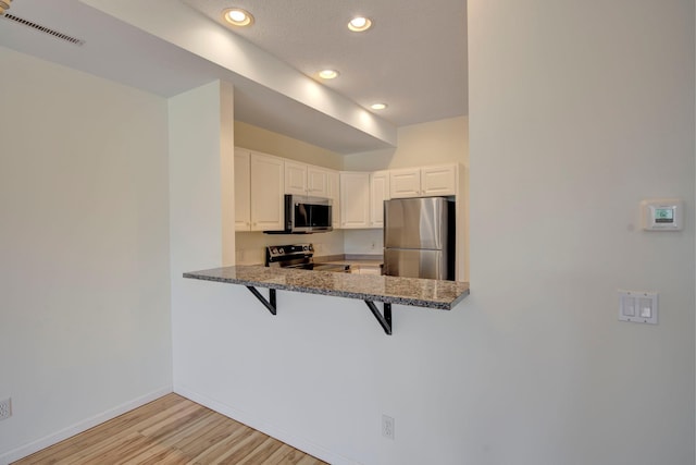 kitchen featuring a breakfast bar area, baseboards, visible vents, appliances with stainless steel finishes, and light wood-type flooring