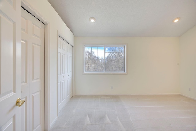 unfurnished bedroom featuring recessed lighting, light colored carpet, baseboards, and a textured ceiling