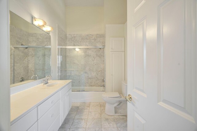 full bathroom with vanity, toilet, marble finish floor, and enclosed tub / shower combo