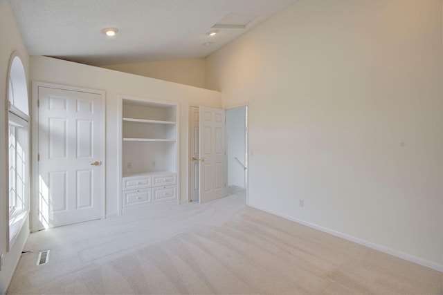 unfurnished bedroom featuring visible vents, lofted ceiling, and light carpet