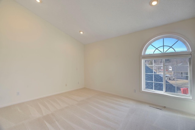 empty room featuring baseboards, visible vents, lofted ceiling, recessed lighting, and light carpet