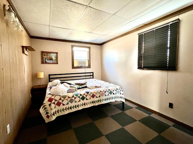 bedroom featuring baseboards, wood walls, ornamental molding, tile patterned floors, and a paneled ceiling