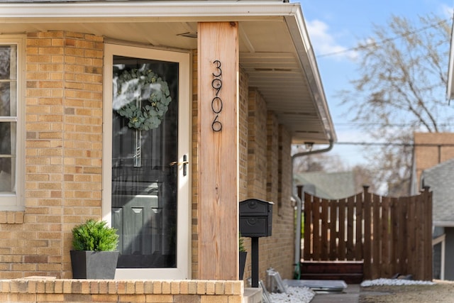 entrance to property with brick siding and fence