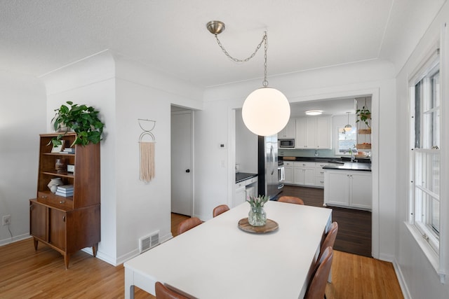 dining space featuring visible vents, baseboards, and wood finished floors