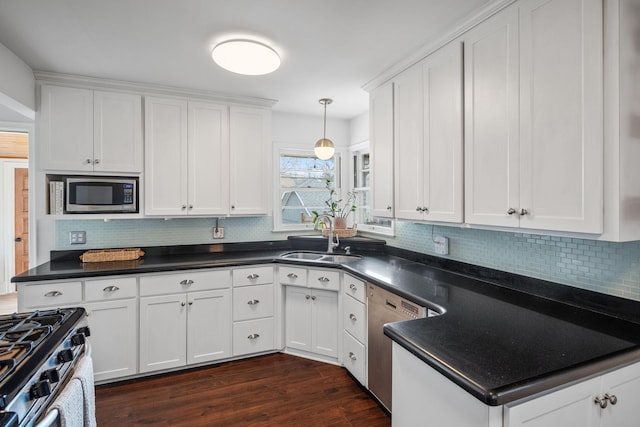 kitchen with a sink, dark countertops, dark wood finished floors, white cabinetry, and appliances with stainless steel finishes