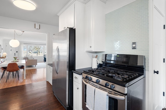 kitchen with stainless steel appliances, decorative backsplash, dark wood-type flooring, white cabinets, and dark countertops