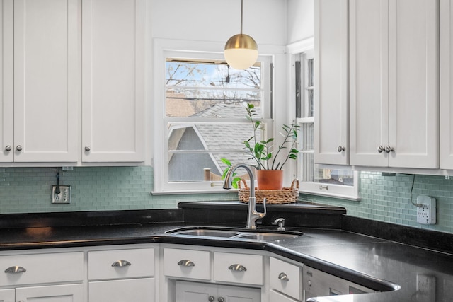 kitchen with white cabinetry, dark countertops, tasteful backsplash, and a sink