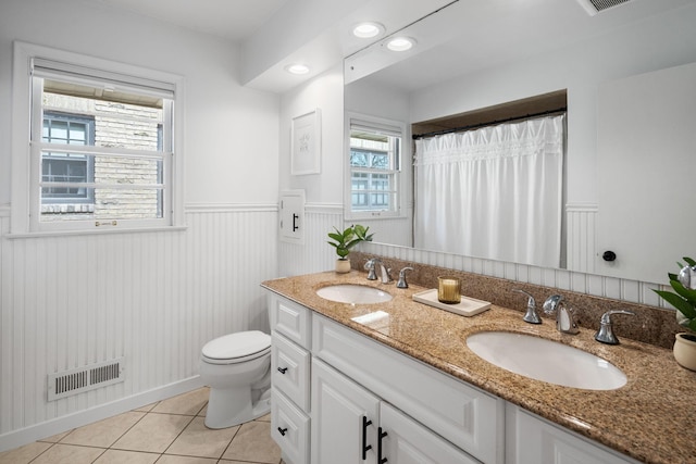 full bath featuring tile patterned floors, visible vents, a wainscoted wall, and a sink