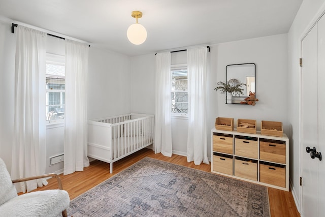 bedroom featuring baseboards, multiple windows, and wood finished floors