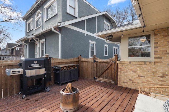 wooden deck featuring fence, a grill, and a gate