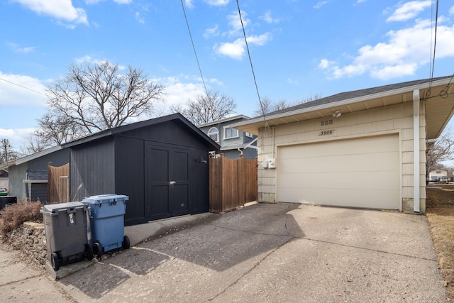 garage with concrete driveway and fence