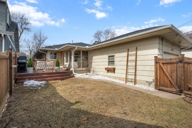 back of house featuring a gate, fence, and a yard