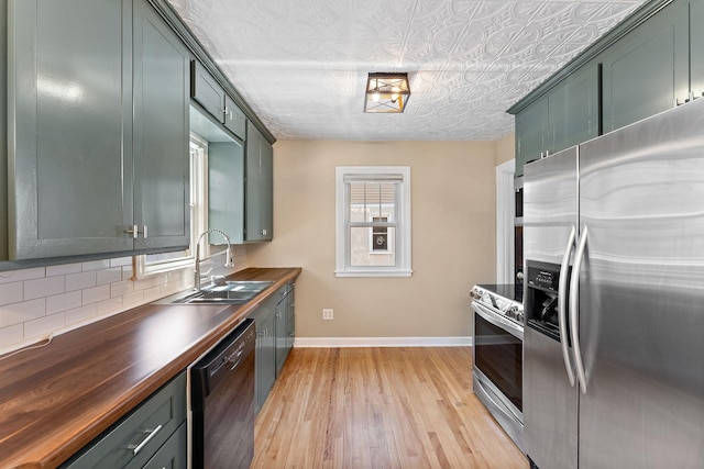 910 Nevada Ave W, Saint Paul, MN 55117 - kitchen featuring appliances with stainless steel finishes, a sink, baseboards, light wood-style flooring, and decorative backsplash