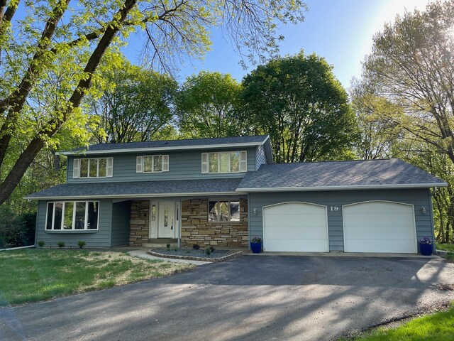 19 Robin Ct, North Mankato, MN 56003 - view of front of home with driveway, an attached garage, stone siding, a porch, and a front yard