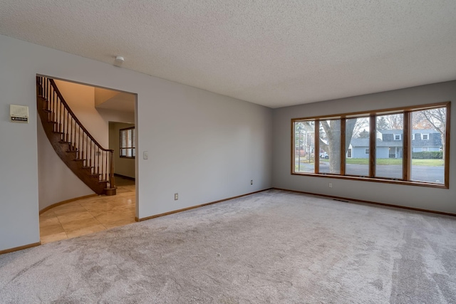 19 Robin Ct, North Mankato, MN 56003 - carpeted spare room with stairs, a textured ceiling, baseboards, and tile patterned flooring