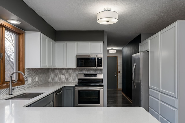 19 Robin Ct, North Mankato, MN 56003 - kitchen with appliances with stainless steel finishes, a sink, light countertops, white cabinetry, and tasteful backsplash