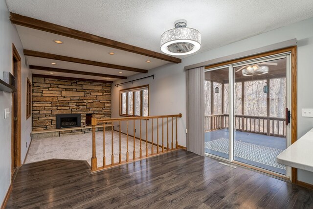 19 Robin Ct, North Mankato, MN 56003 - unfurnished living room with wood finished floors, beam ceiling, a fireplace, plenty of natural light, and a textured ceiling